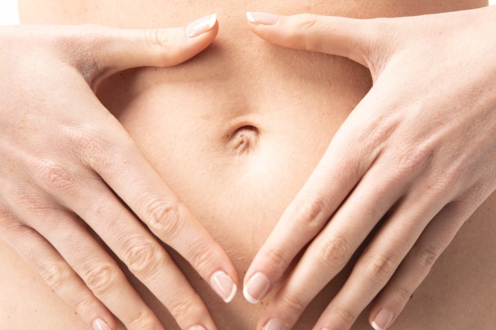 Mani di donna a forma di cuore intorno all’ombelico