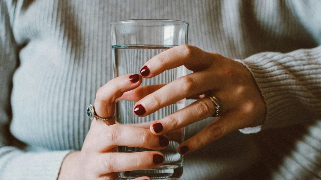 Donna che tiene un bicchiere d’acqua tra le mani