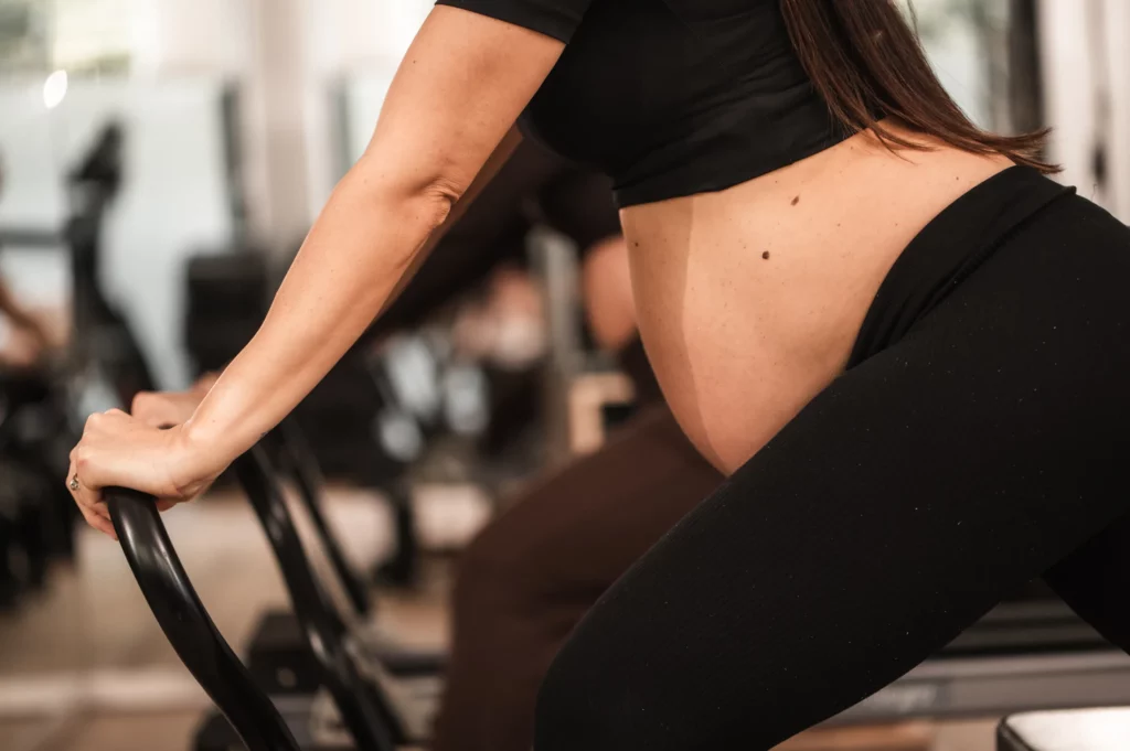 Esercizio sul Reformer in gravidanza, con la mano sul ventre