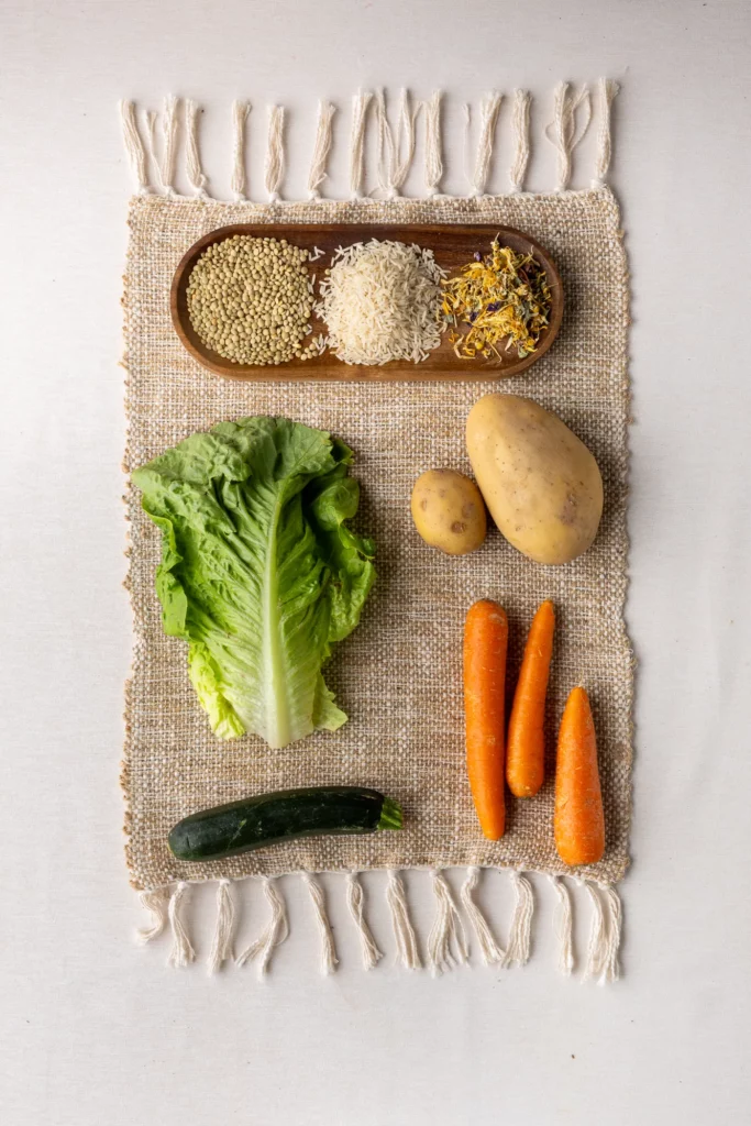 Legumi e cereali su un vassoio di legno con patate, carote, lattuga e cetriolo