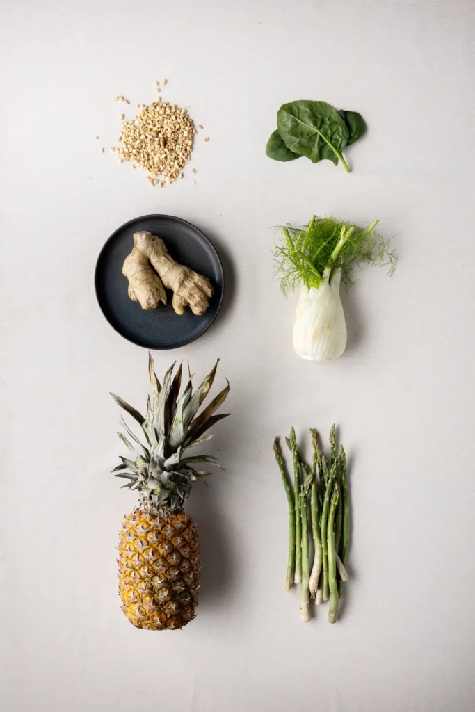Spinaci, finocchio, asparagi, cereali, zenzero e ananas su fondo chiaro