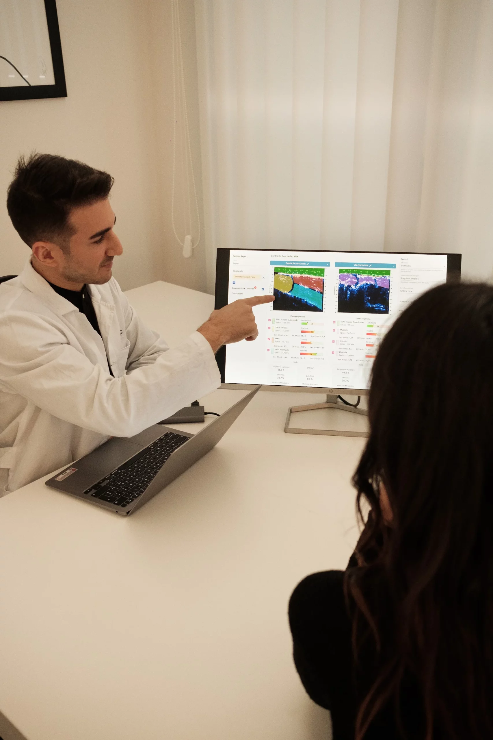 Il nutrizionista Linfa indica sullo schermo i dati della composizione corporea a una cliente
